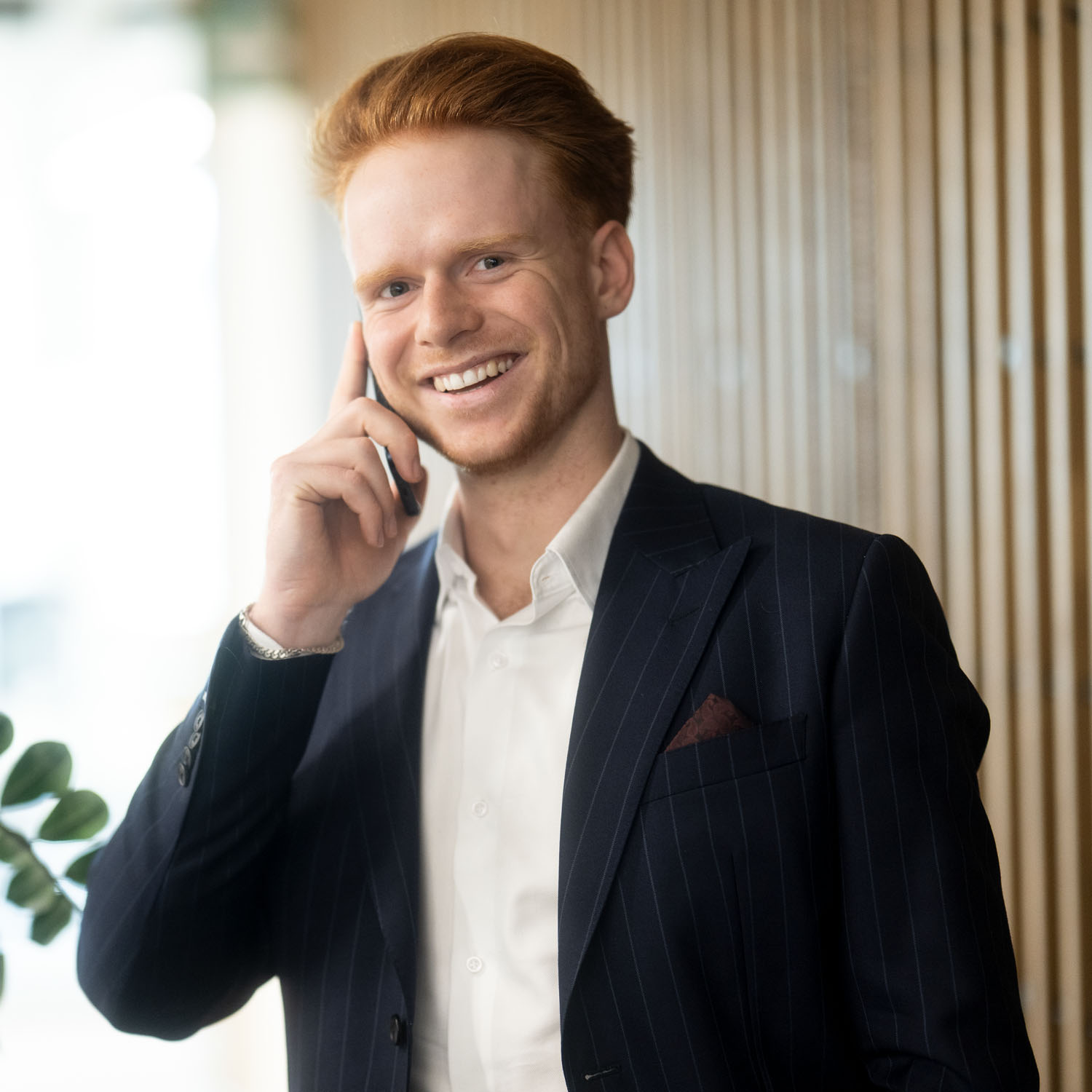 Leo Markl telefoniert mit seinem Smartphone und lächelt dabei in die Kamera