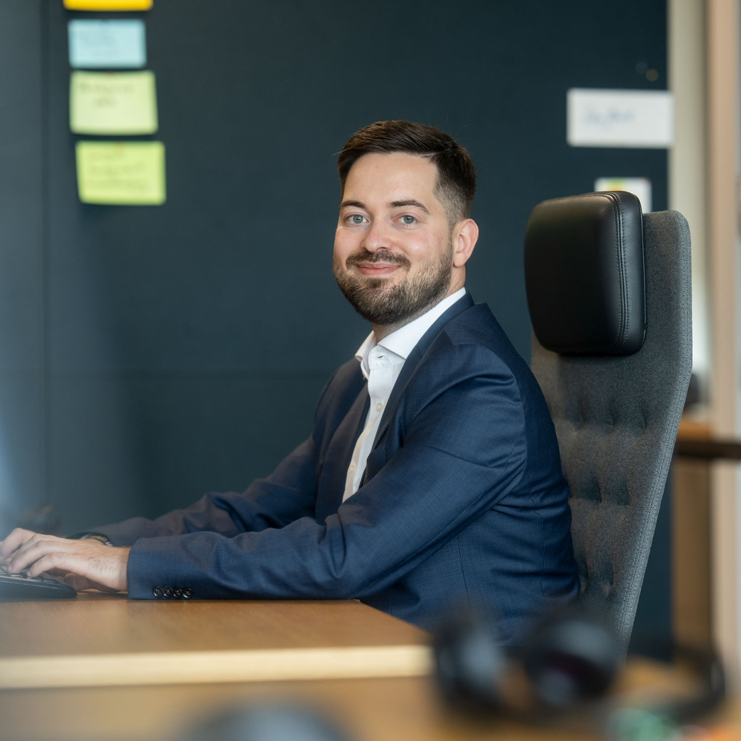 Lukas Trafi am Arbeitsplatz, er lächelt in die Kamera.