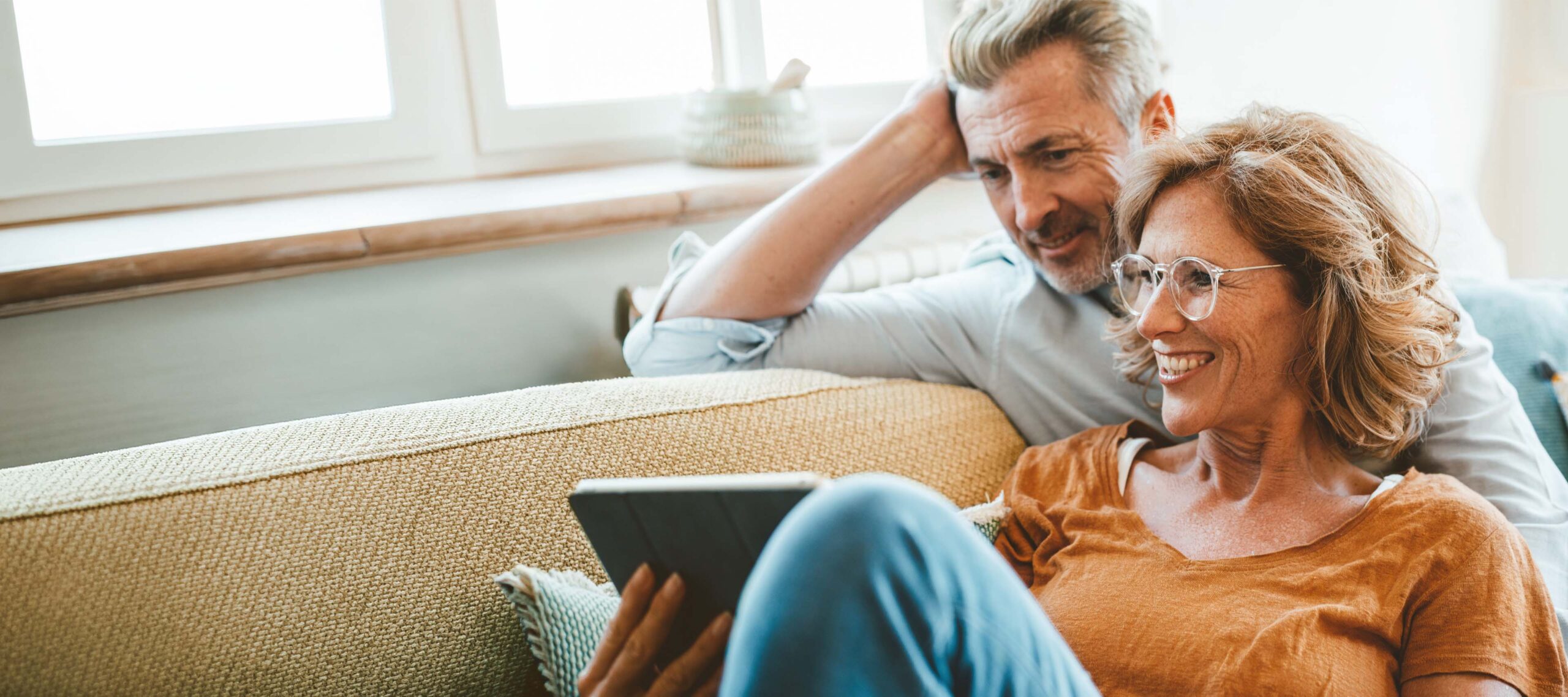 Ein Pärchen sitzt auf dem Sofa und schaut zusammen auf ein Tablet.