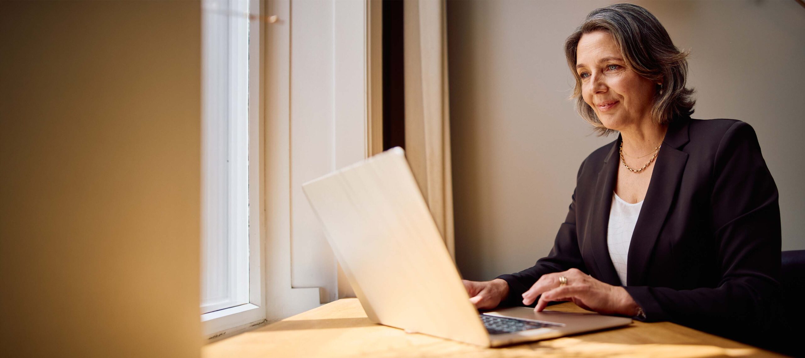 Eine Dame im Arbeitszimmer schaut auf Ihren Laptop