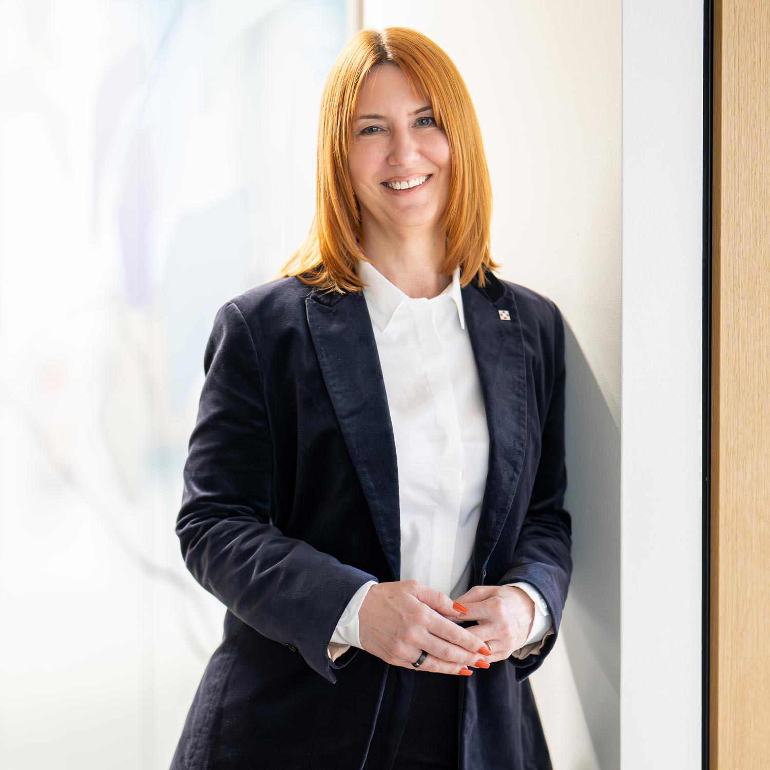 Nadine Schwab lehnt sich an einer Wand und schaut freundlich in die Kamera.
