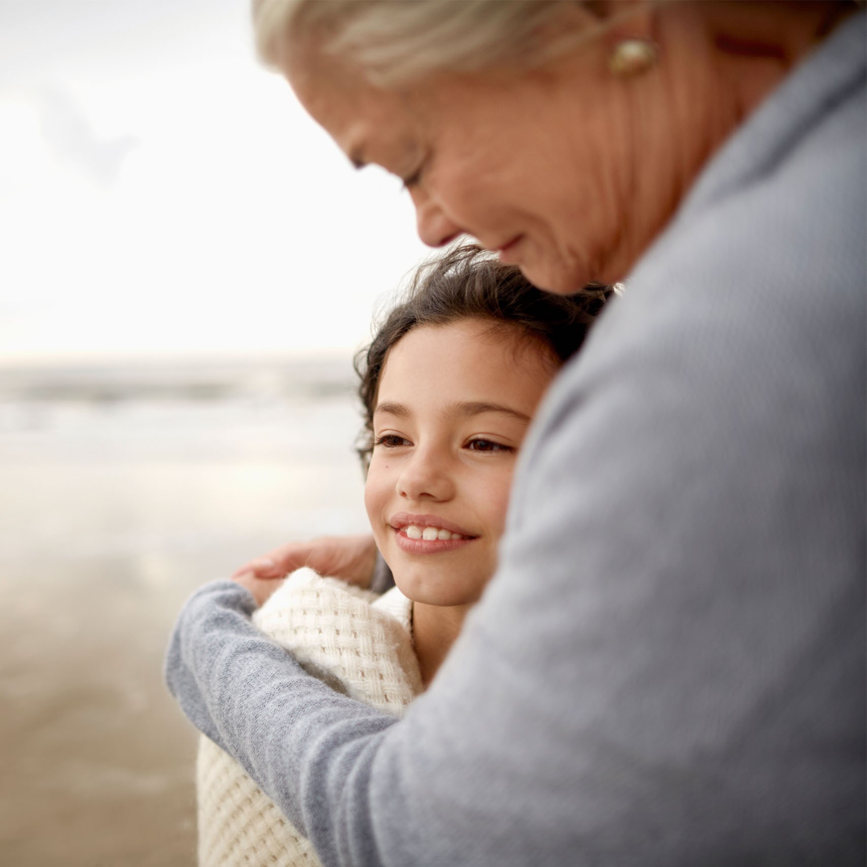 Eine ältere Dame umarmt ihre Enkeltochter am Strand